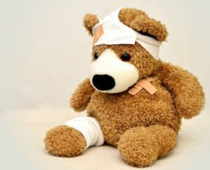 Teddybär mit Pflaster und Binde um Kopf und Bein